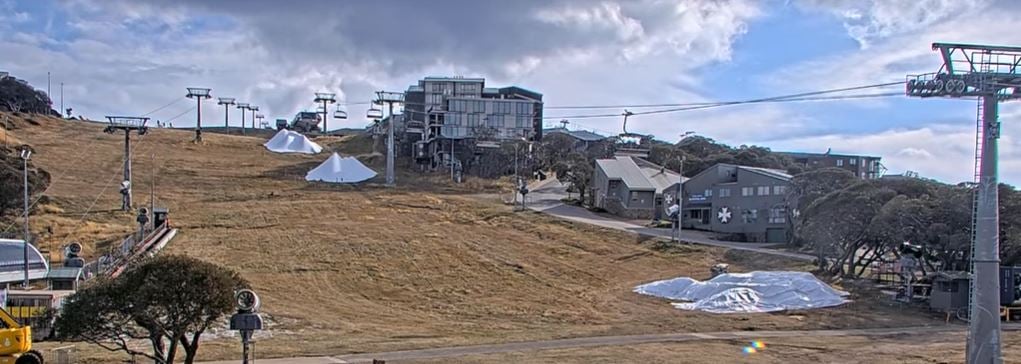 Live view from the Bourke Street webcam at Mt Buller showing growing piles of snow in readiness for the 2024 snow season