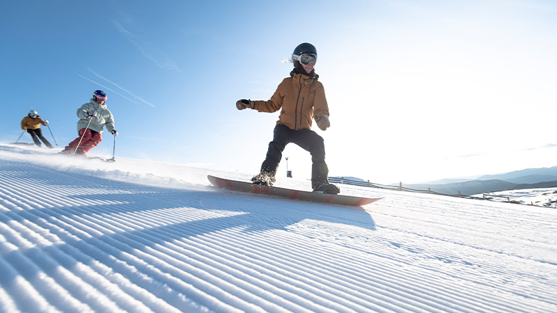Skiers and snowboarder riding the slopes on Mt Buller on groomed snow